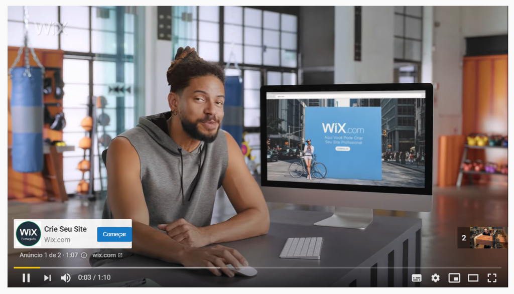 advertisement of the wix website creation platform on Youtube. A black man is sitting holding a mouse in front of a computer with the Wix logo on the screen