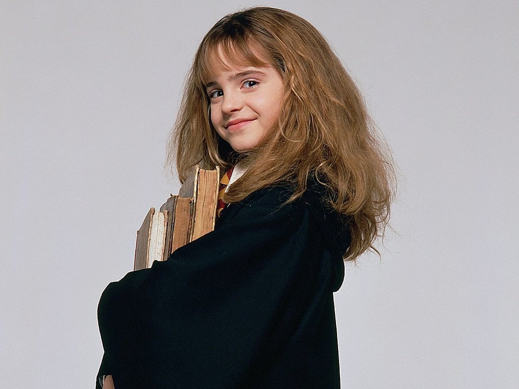 Hermione Granger smiles with book in front of gray background